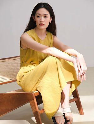 Three linen dresses on hangers in apricot, yellow, and green shades