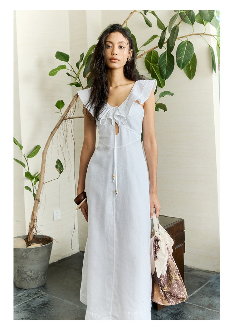 Woman in white linen dress with ruffle sleeves and tie-front cutout