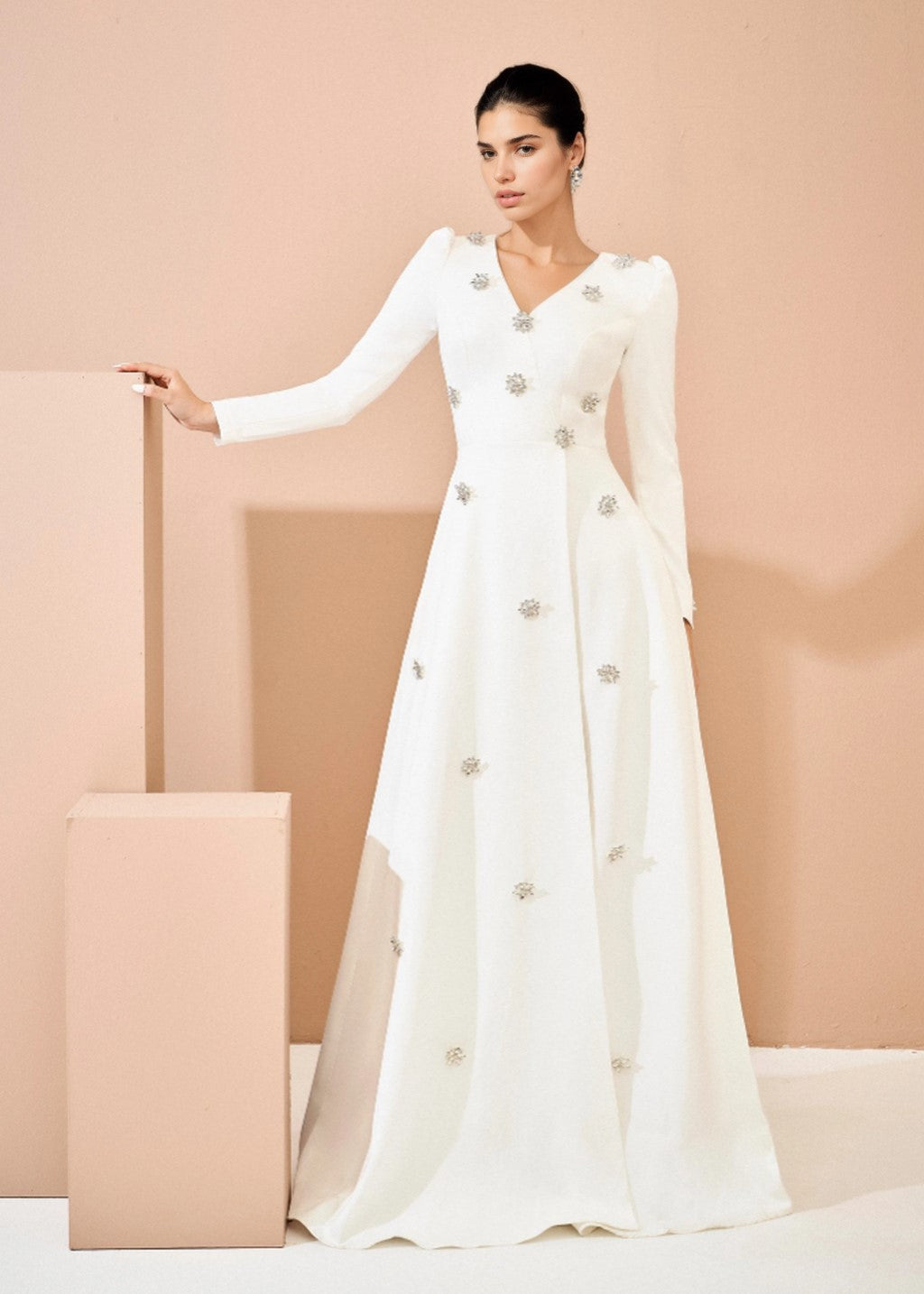 The long-sleeved wedding dress is adorned with rhinestones.