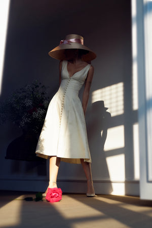 Flared natural-fiber midi dress worn in a rustic garden