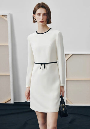 Petite woman in ivory straight-cut dress with black trim