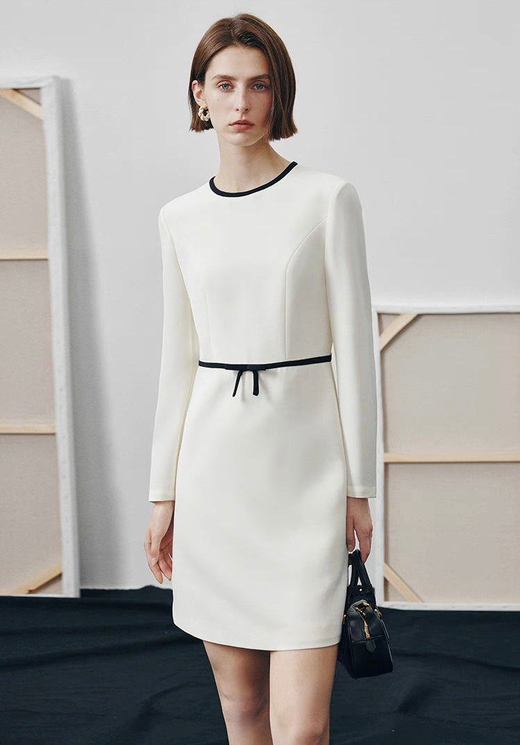 Petite woman in ivory straight-cut dress with black trim