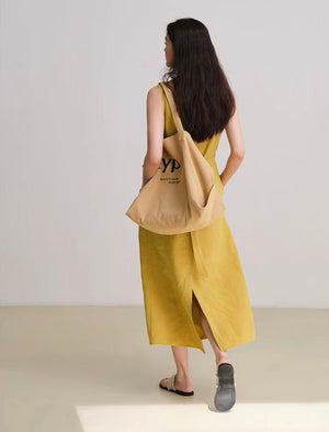 Side view of yellow knot dress styled with black sandals