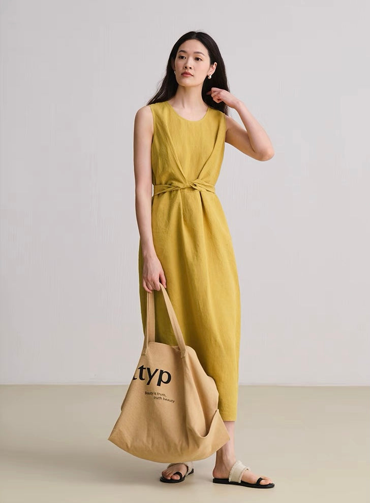 Woman wearing wheat yellow sleeveless linen dress with front knot detail
