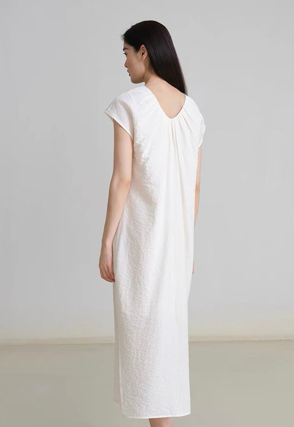 Model wearing white gathered V-neck linen dress with side slits