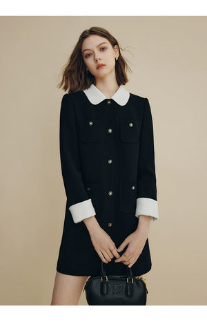 Front view of black coat dress with white collar and cuffs