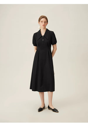 Close-up of black linen dress showing pointed collar and pearl-accented buttons