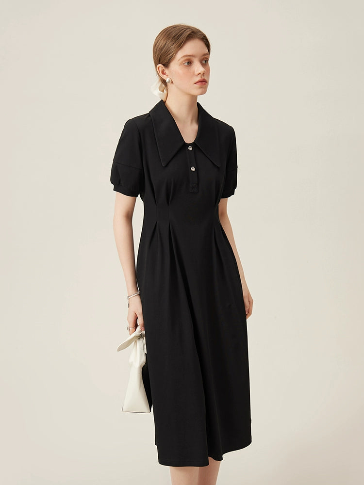 Close-up of black linen dress showing pointed collar and pearl-accented buttons