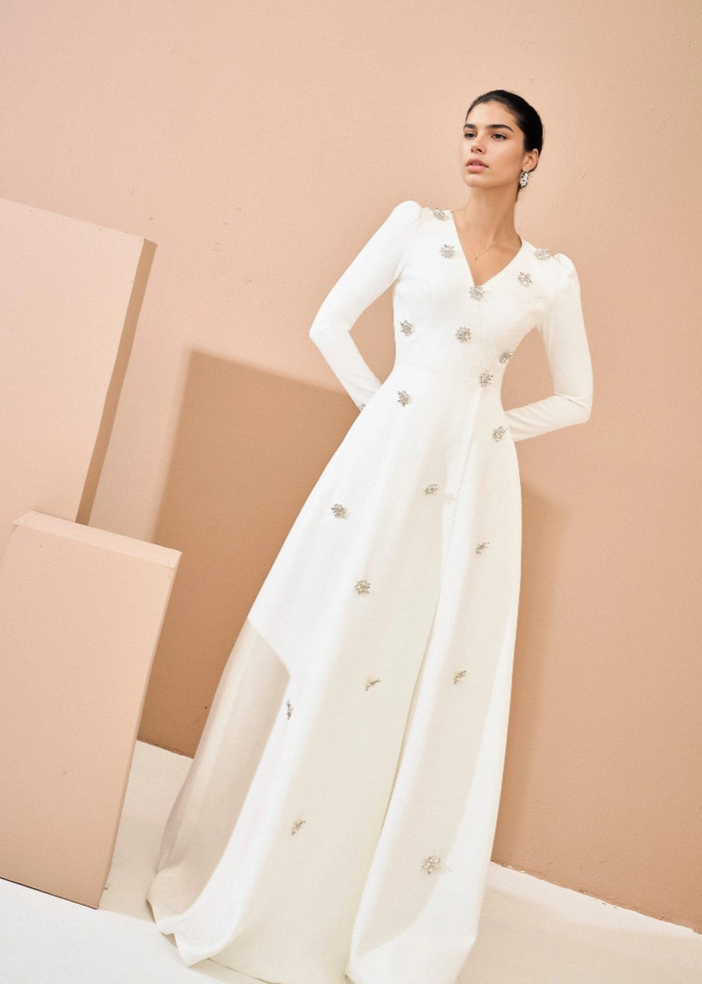 The long-sleeved wedding dress is adorned with rhinestones.